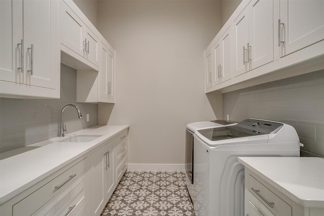 washroom featuring baseboards, independent washer and dryer, a sink, and cabinet space