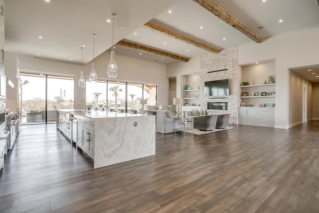 kitchen featuring dark wood-type flooring, built in shelves, a spacious island, and a fireplace