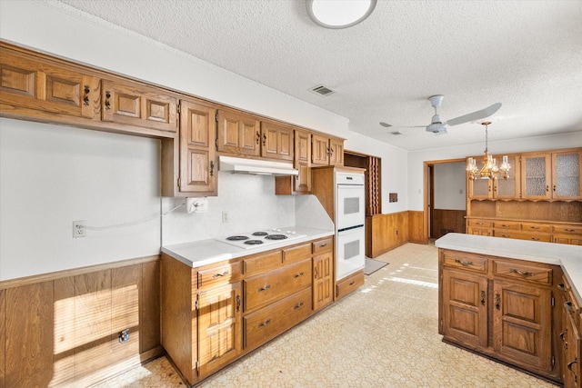 1611 Royal Mile Ct, Arlington, TX 76015 - kitchen featuring a wainscoted wall, white appliances, under cabinet range hood, a ceiling fan, and brown cabinets