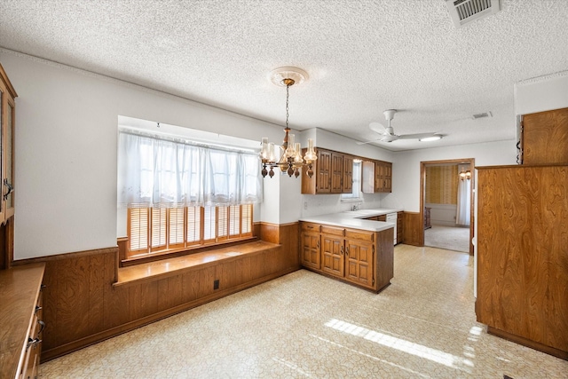 1611 Royal Mile Ct, Arlington, TX 76015 - kitchen with wainscoting, brown cabinetry, ceiling fan, a textured ceiling, and a chandelier