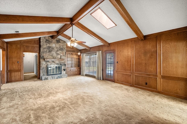 1611 Royal Mile Ct, Arlington, TX 76015 - unfurnished living room with wooden walls, ceiling fan, a fireplace, a skylight, and carpet floors