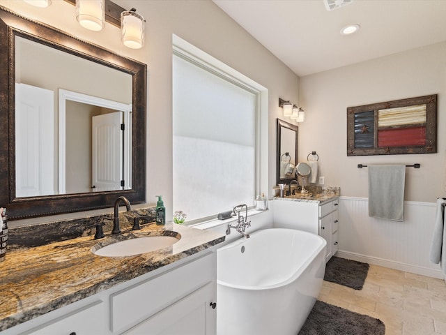 141 County Road 3481, Paradise, TX 76073 - full bathroom featuring stone tile flooring, two vanities, a sink, a freestanding bath, and wainscoting