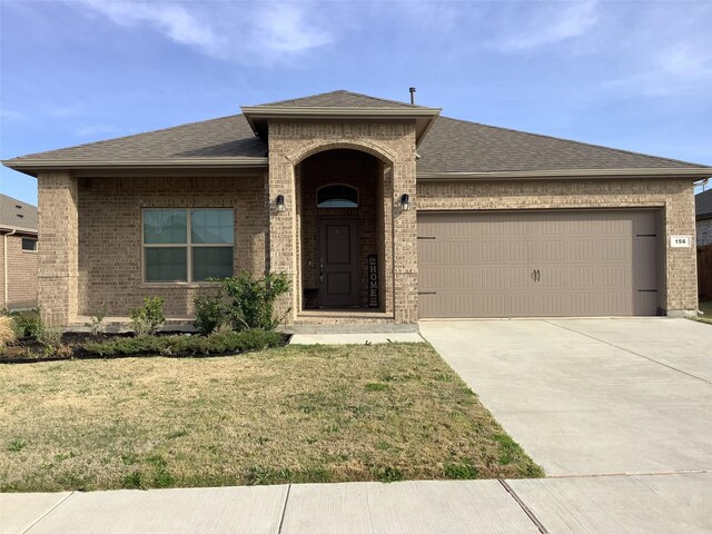 156 Hawksbill Ln, Rhome, TX 76078 - view of front of home featuring an attached garage, concrete driveway, a front yard, brick siding, and roof with shingles