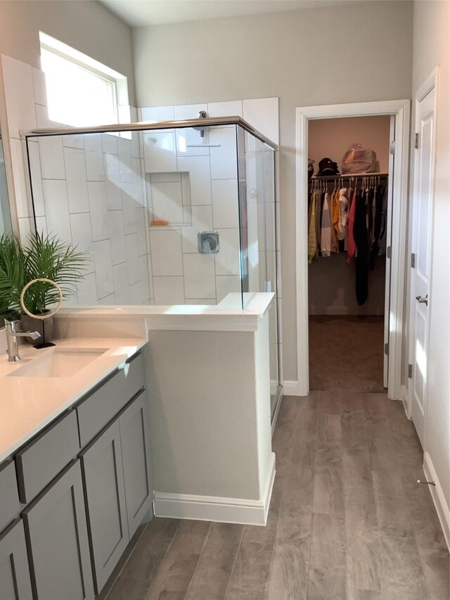 156 Hawksbill Ln, Rhome, TX 76078 - full bathroom with baseboards, wood finished floors, vanity, a stall shower, and a walk in closet