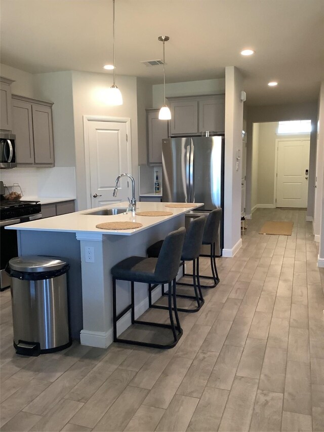 156 Hawksbill Ln, Rhome, TX 76078 - kitchen with gray cabinets, a kitchen bar, a sink, and stainless steel appliances