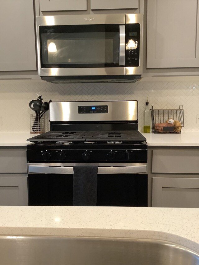 156 Hawksbill Ln, Rhome, TX 76078 - kitchen with tasteful backsplash, appliances with stainless steel finishes, gray cabinetry, and light stone counters