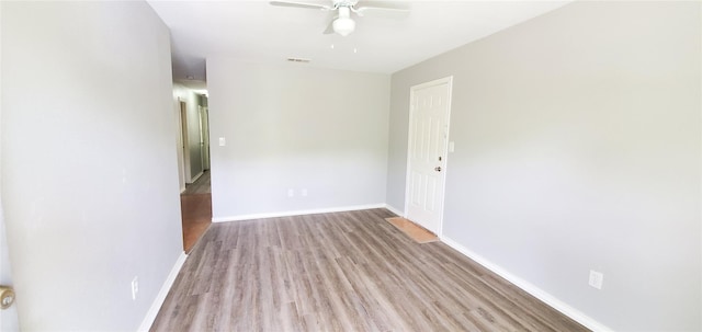 empty room featuring wood finished floors, visible vents, baseboards, and ceiling fan