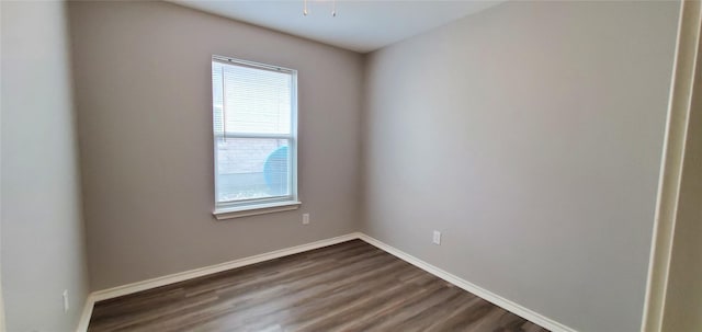 unfurnished room featuring dark wood-style flooring and baseboards