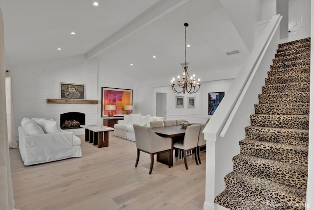 dining space with a notable chandelier, light wood-type flooring, stairway, visible vents, and vaulted ceiling with beams