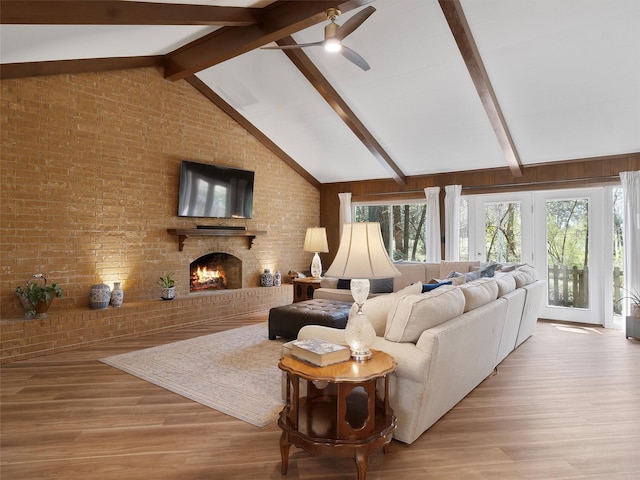 living room featuring a fireplace, wood finished floors, a ceiling fan, brick wall, and vaulted ceiling with beams