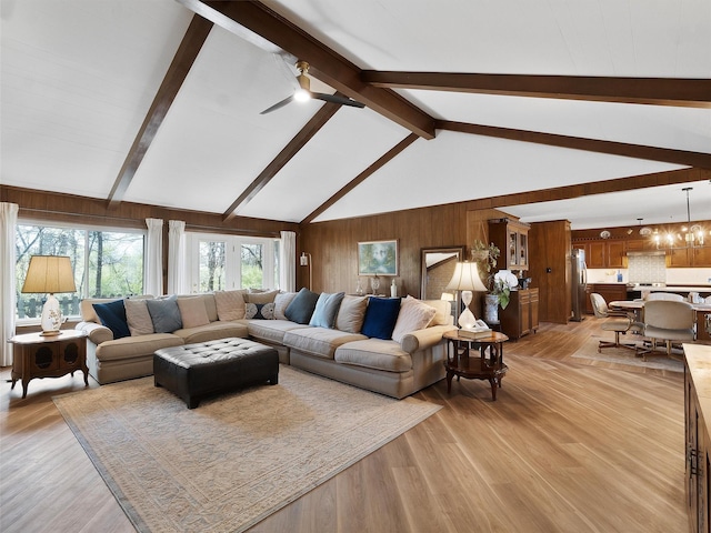 living room with beamed ceiling, light wood-style floors, wood walls, and a ceiling fan
