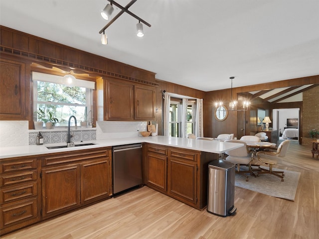 kitchen featuring light countertops, a sink, stainless steel dishwasher, and light wood finished floors