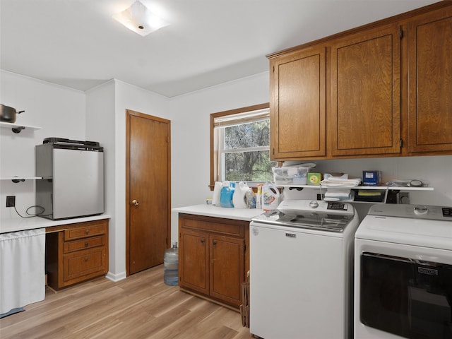 washroom featuring cabinet space, washing machine and dryer, and light wood-style floors