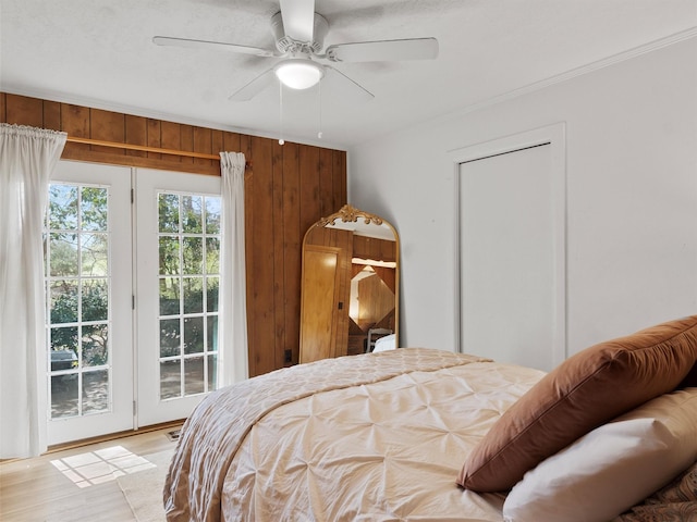 bedroom with wood walls, ceiling fan, access to outside, ornamental molding, and light wood-style floors