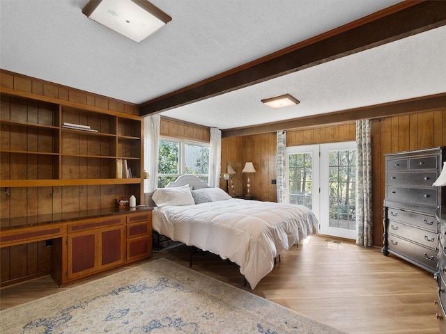 bedroom with light wood-style flooring, wood walls, access to outside, and beamed ceiling