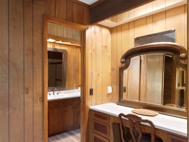 bathroom with vanity, wooden walls, and wood finished floors