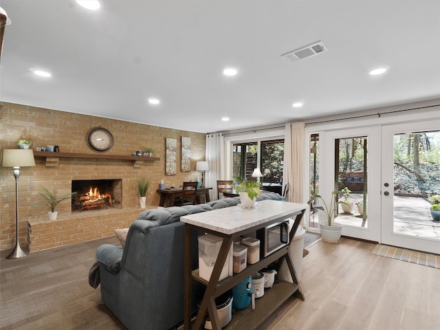 living area featuring a wealth of natural light, brick wall, and visible vents