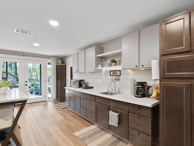 kitchen featuring visible vents, light countertops, a sink, and open shelves