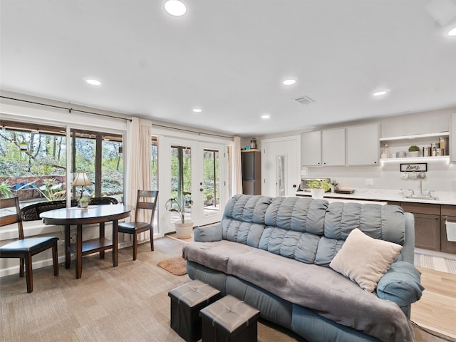 living area with visible vents, french doors, recessed lighting, and light colored carpet