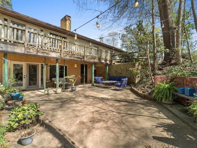 back of house featuring a chimney, brick siding, fence, and a patio area