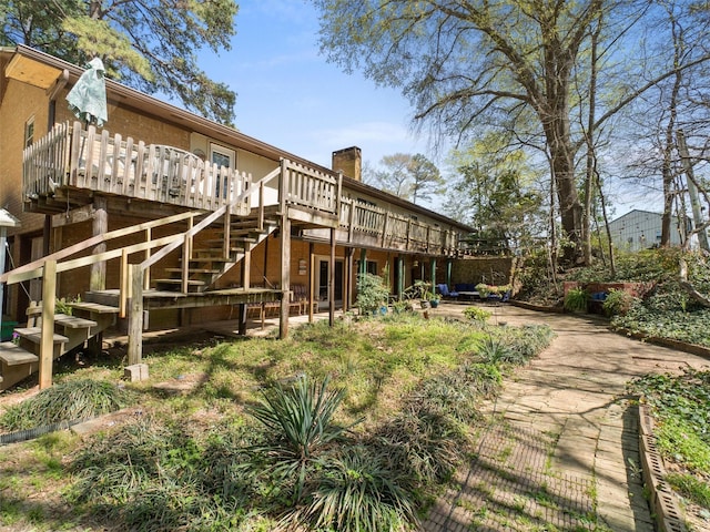 back of house featuring a chimney, a wooden deck, and stairway