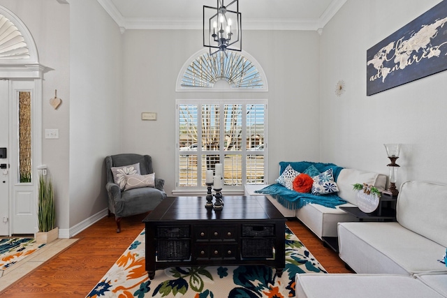 living area featuring baseboards, a notable chandelier, crown molding, and wood finished floors