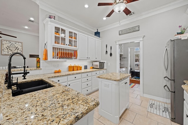 kitchen featuring freestanding refrigerator, ornamental molding, a sink, and a ceiling fan