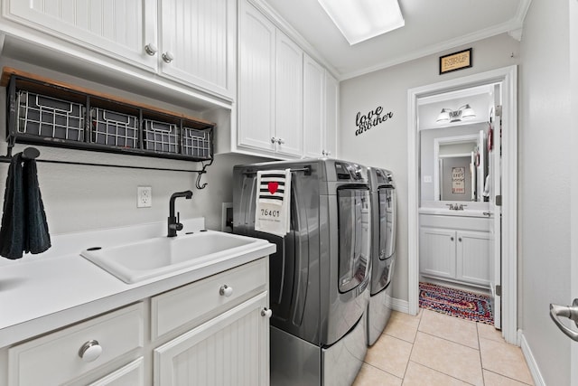 laundry room featuring ornamental molding, a sink, cabinet space, separate washer and dryer, and light tile patterned floors