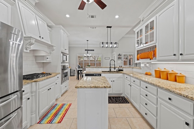 kitchen with crown molding, a sink, a peninsula, stainless steel appliances, and ceiling fan with notable chandelier