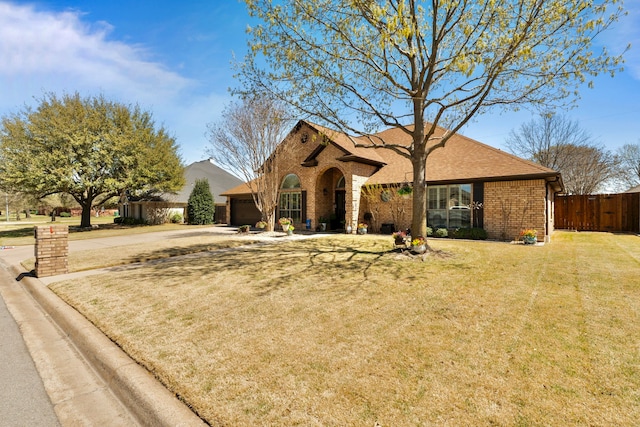 view of front of property with a front lawn, fence, an attached garage, and brick siding