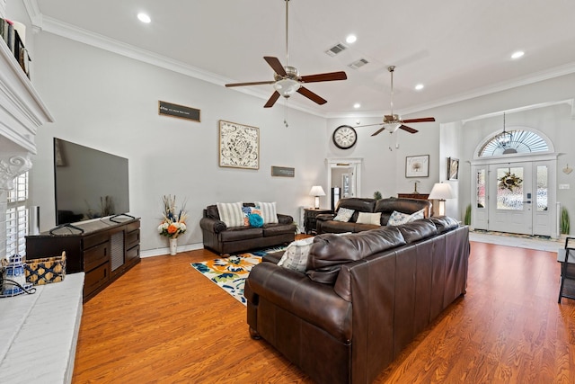 living room featuring ceiling fan, visible vents, crown molding, and light wood finished floors