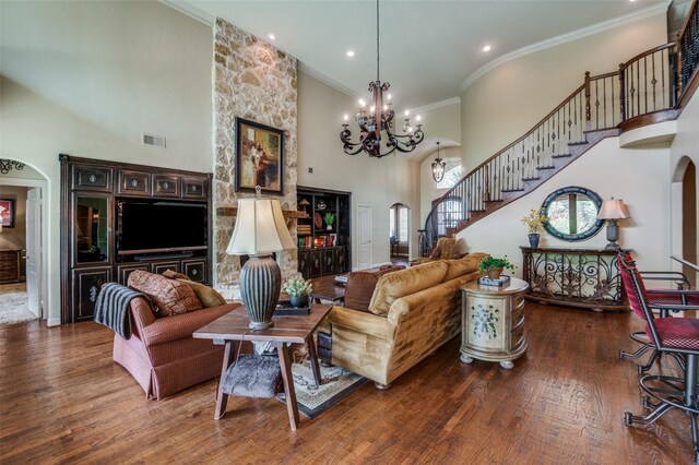 living area featuring crown molding, stairs, wood finished floors, a towering ceiling, and visible vents
