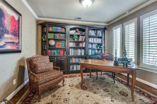 office space featuring visible vents, baseboards, wood finished floors, and ornamental molding