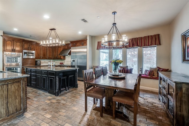 dining area featuring recessed lighting, brick floor, and an inviting chandelier
