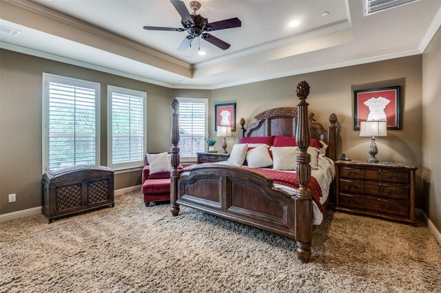 carpeted bedroom with baseboards, ornamental molding, a tray ceiling, and visible vents