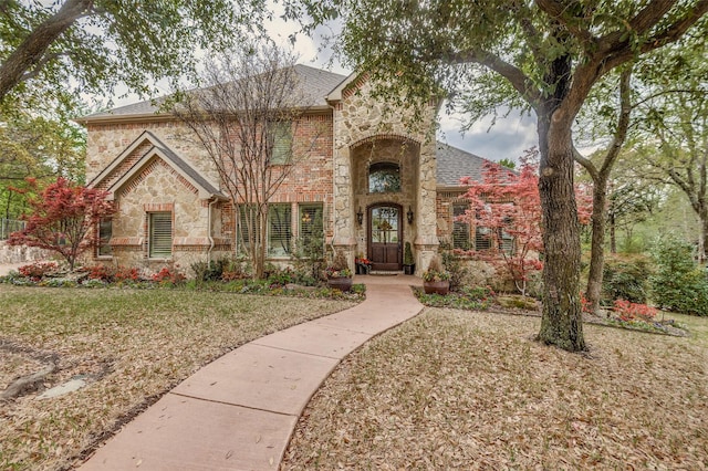 view of front of house with stone siding, a shingled roof, and a front lawn