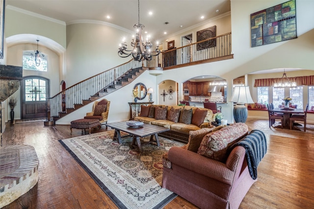 living area featuring stairs, a high ceiling, arched walkways, and a chandelier