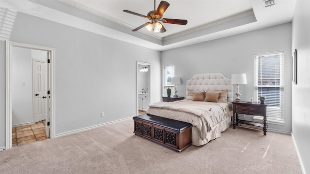 bedroom with carpet flooring, ornamental molding, a tray ceiling, and multiple windows
