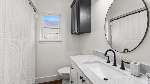bathroom featuring toilet, curtained shower, vanity, wood finished floors, and baseboards