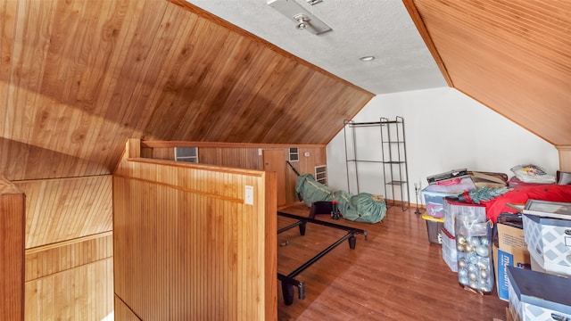 bonus room with a textured ceiling, wood walls, vaulted ceiling, and wood finished floors