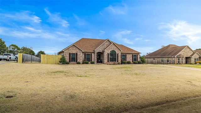 view of front of home with a gate, fence, brick siding, and roof with shingles