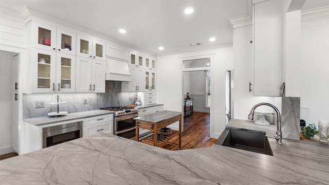 kitchen with light stone counters, a sink, wood finished floors, appliances with stainless steel finishes, and decorative backsplash