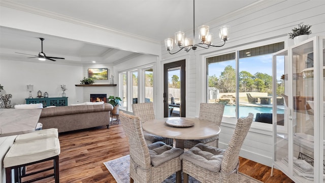 dining room featuring wood finished floors, a brick fireplace, ornamental molding, and a wealth of natural light
