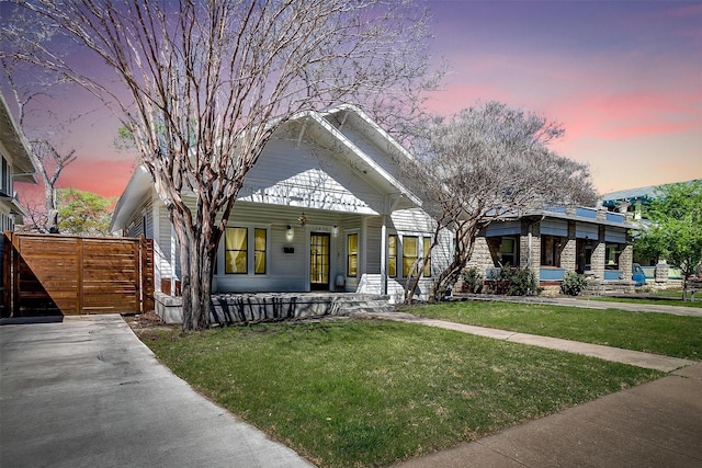 bungalow-style home featuring covered porch and a yard