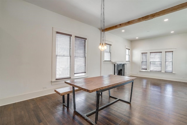 dining area featuring dark wood-style flooring, baseboards, a fireplace, beam ceiling, and a healthy amount of sunlight