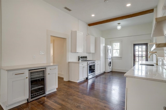 kitchen featuring dark wood-style flooring, gas range, wine cooler, beamed ceiling, and stacked washer / dryer
