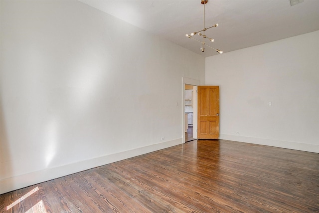 unfurnished room featuring a high ceiling, baseboards, a chandelier, and wood finished floors