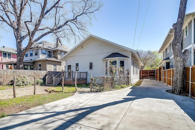 view of front of home with driveway, fence, and a deck