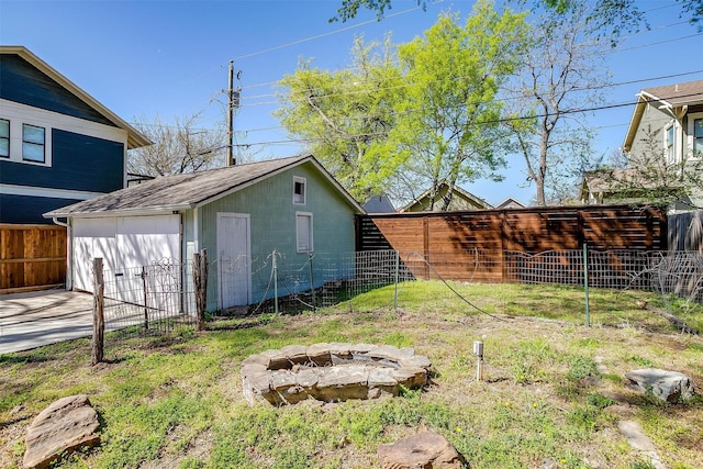 view of yard with fence, an outdoor fire pit, an outbuilding, and a garage