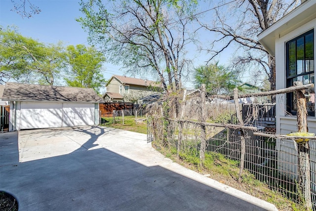 exterior space featuring fence, driveway, an outdoor structure, and a garage